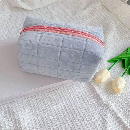 Cute plush makeup bag in light blue with a pink zipper for stylish storage of cosmetics