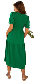 Back view of a model wearing a dark green smocked dress with puff sleeves and tiered design