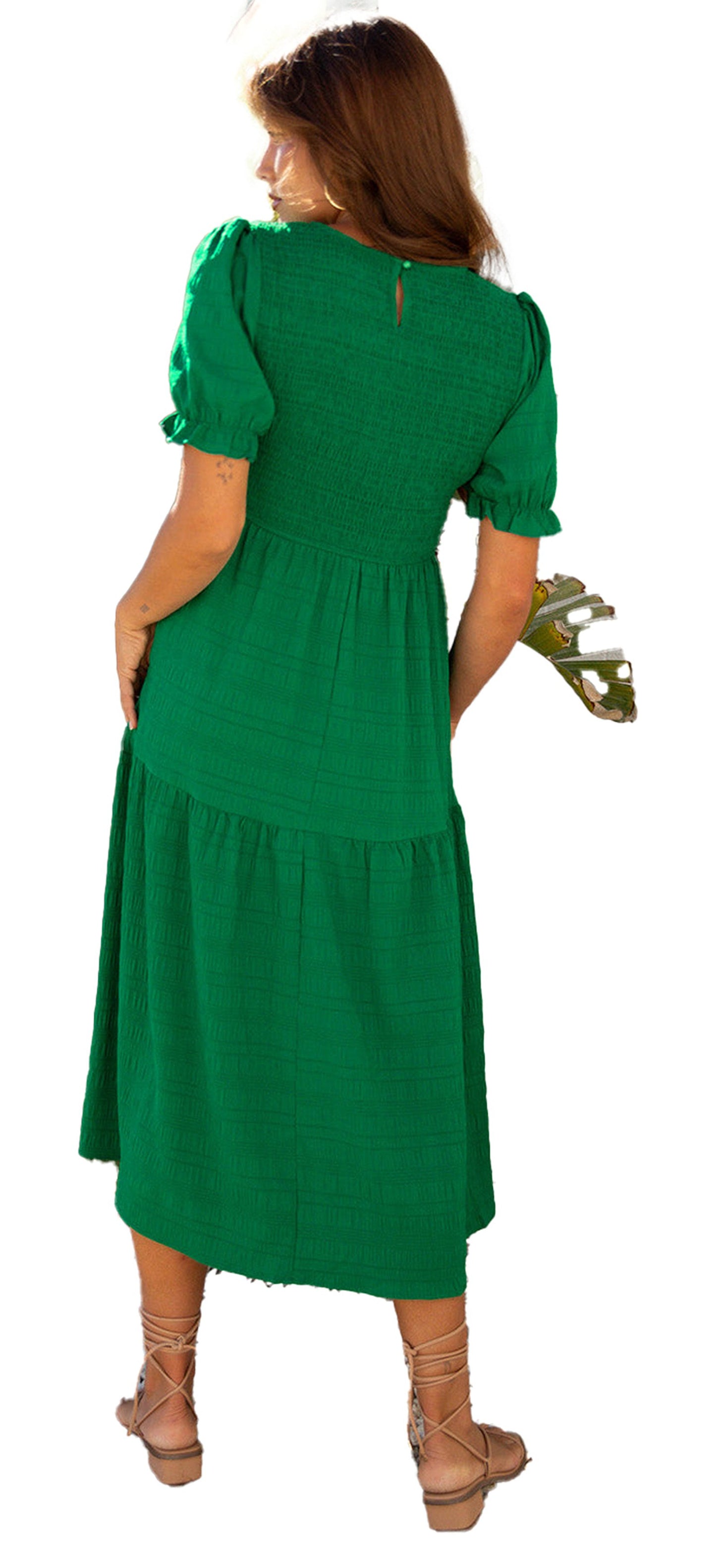 Back view of a model wearing a dark green smocked dress with puff sleeves and tiered design
