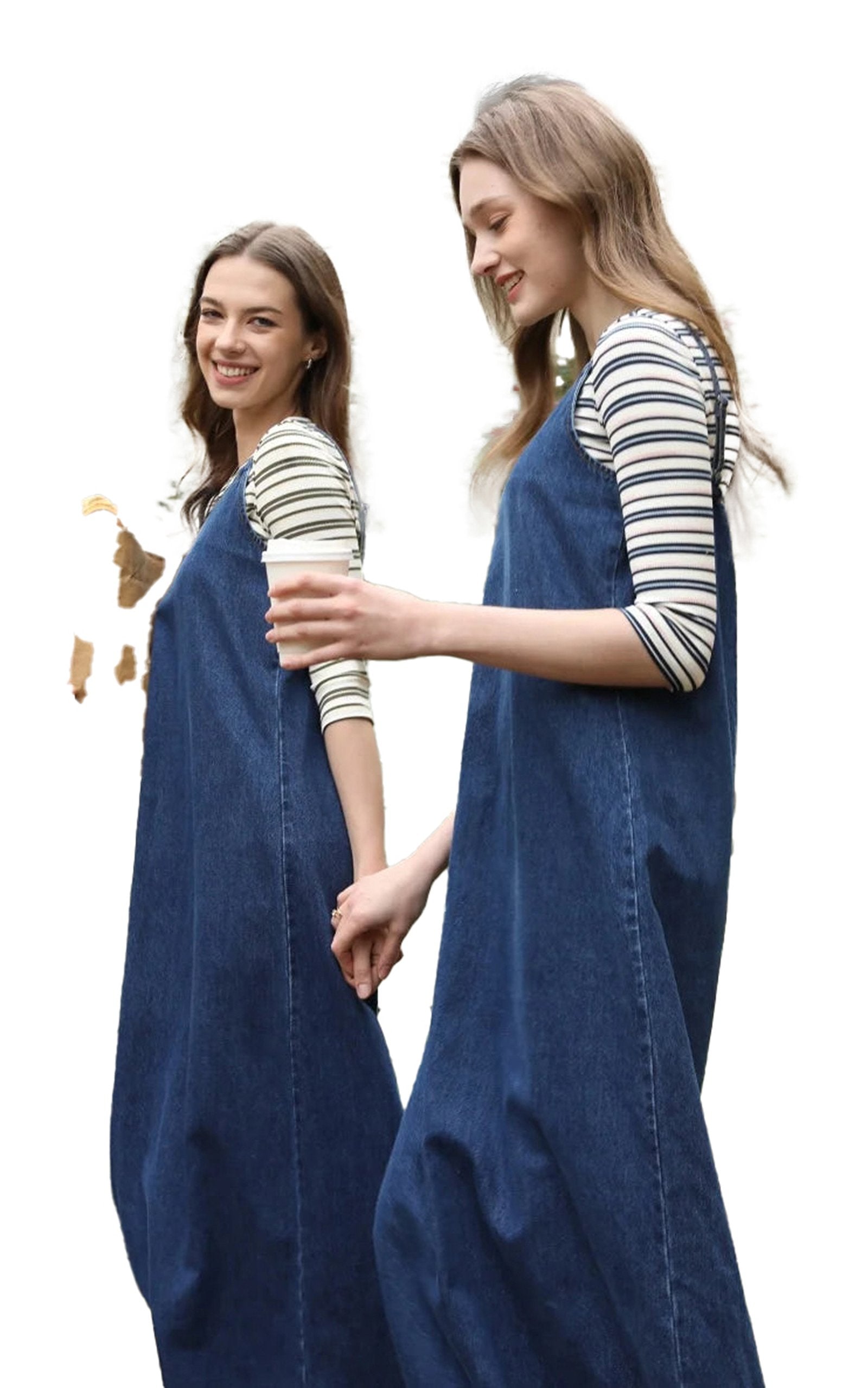Two models wearing a denim jumper dress for women, styled casually with striped shirts underneath