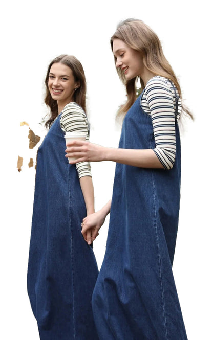 Two models wearing a denim jumper dress for women, styled casually with striped shirts underneath