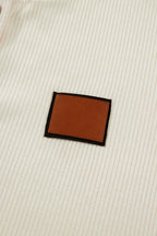 Close-up of a beige fabric with a leather patch, featured on a LuckeLadybug denim shirt