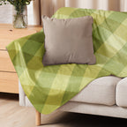 LuckeLadybug green sherpa blanket with diamond pattern bedding design draped over beige couch with brown pillow
