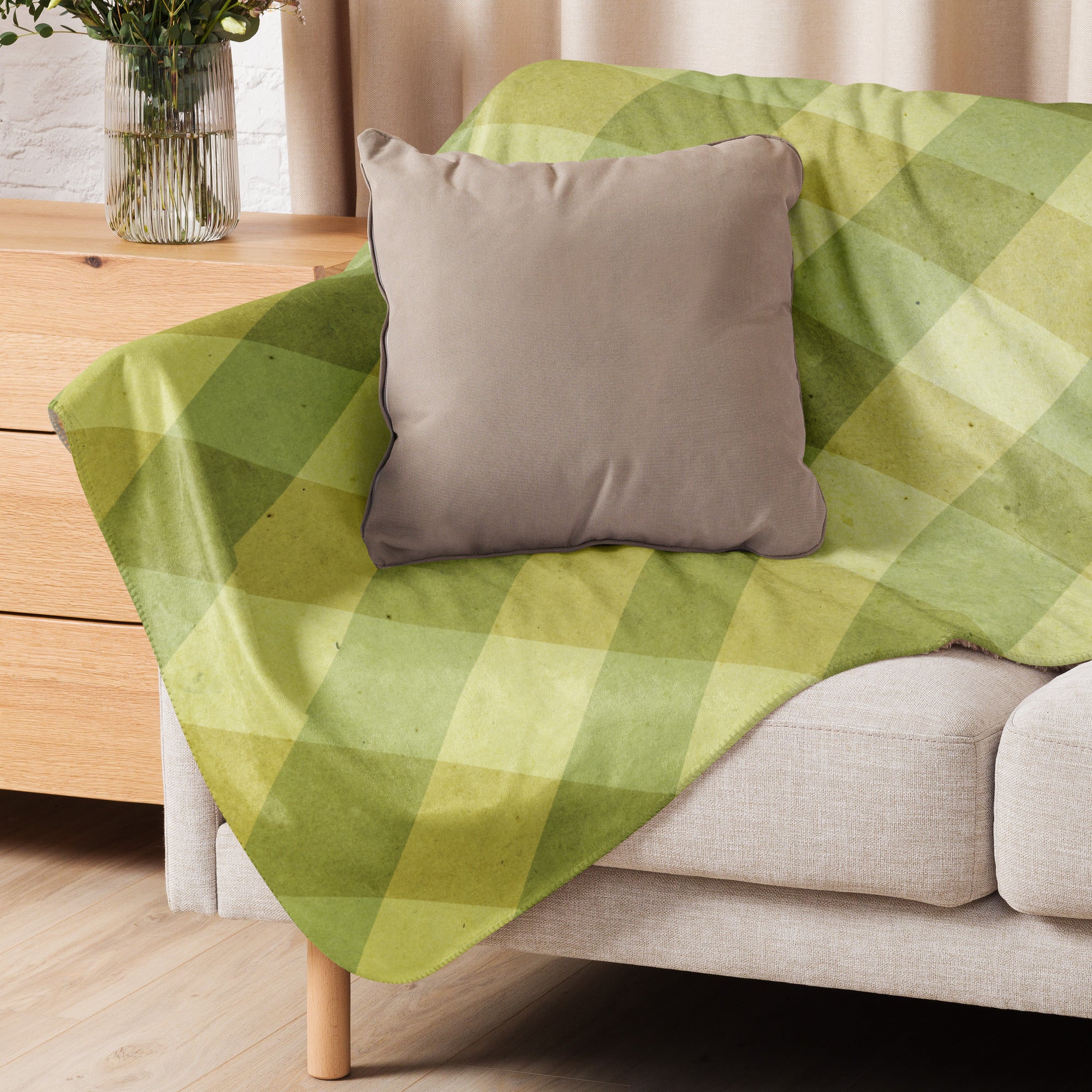 LuckeLadybug green sherpa blanket with diamond pattern bedding design draped over beige couch with brown pillow