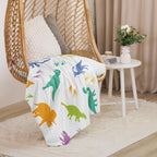 LuckeLadybug dinosaur sherpa blanket with colorful dinosaur prints draped over a hanging chair