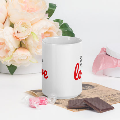 White do what you love coffee mug by LuckeLadybug with red text, placed on a newspaper with chocolates and candy nearby