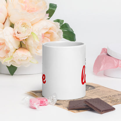 White do what you love coffee mug with red text on table next to flowers chocolate and candy