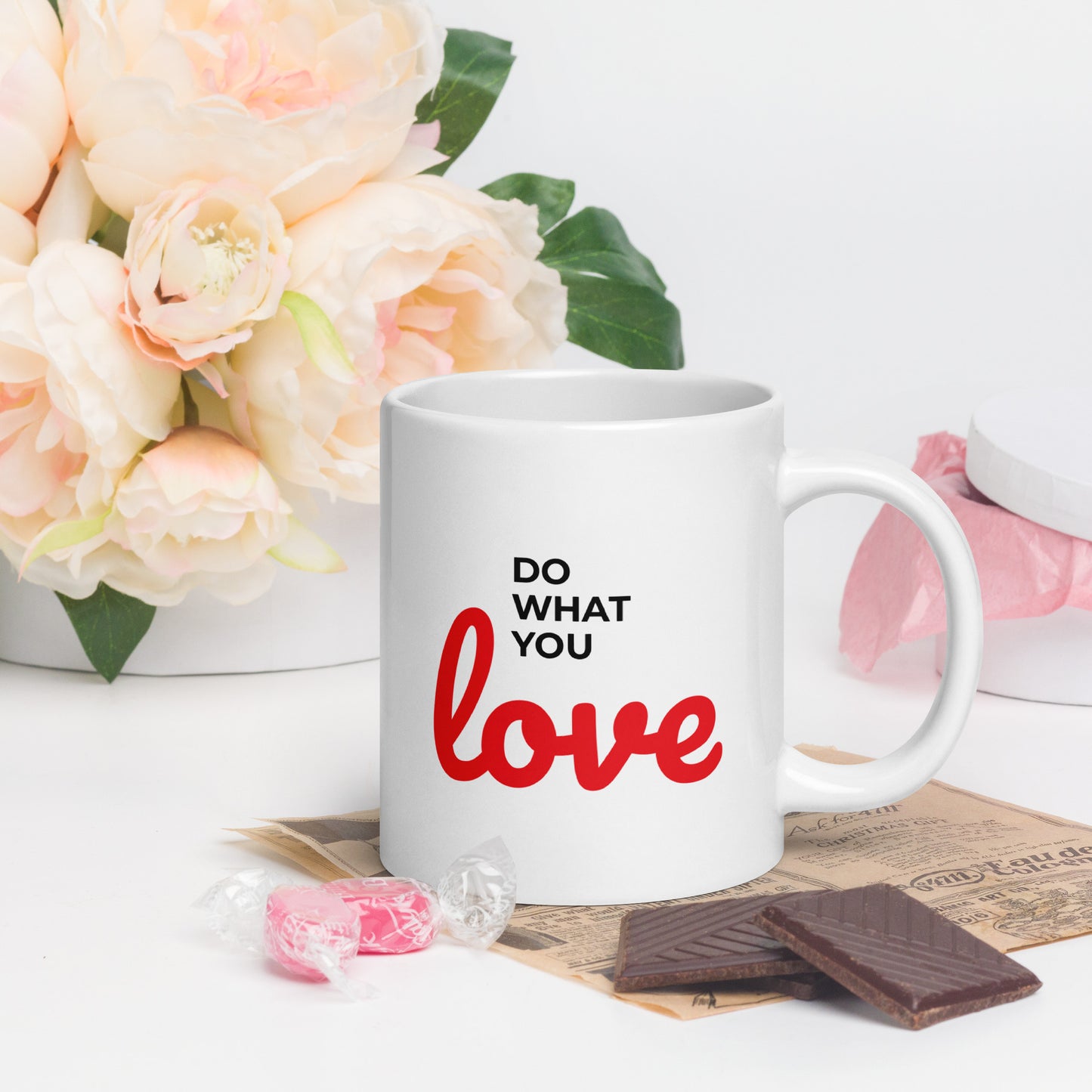 LuckeLadybug do what you love coffee mug with white ceramic and red black text next to flowers and chocolates