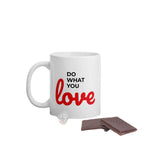 White do what you love coffee mug with black and red text beside chocolate pieces