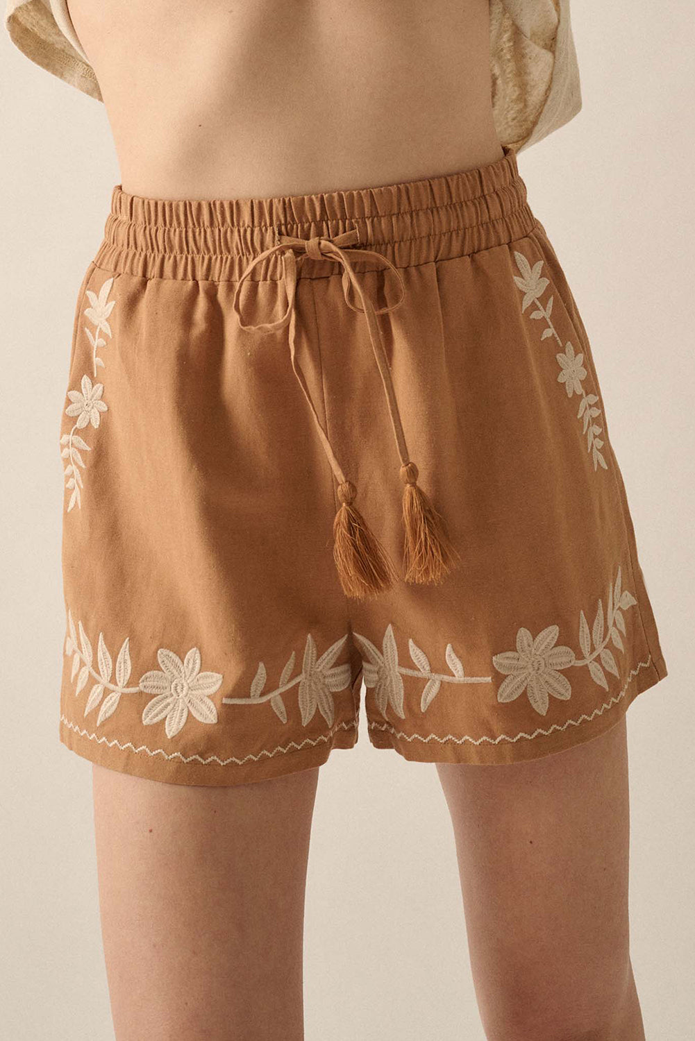 LuckeLAdybug LLC embroidered shorts in tan with floral design and tassel drawstring