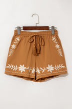 LuckeLAdybug LLC embroidered shorts with floral designs and tassel drawstring in a warm brown color