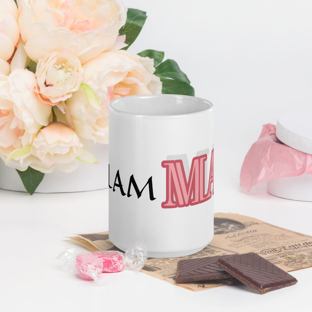 White mug with pink and black glam ma coffee mug text beside flowers and chocolates