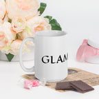 White ceramic glam ma coffee mug by LuckeLadybug with black text surrounded by flowers and chocolates