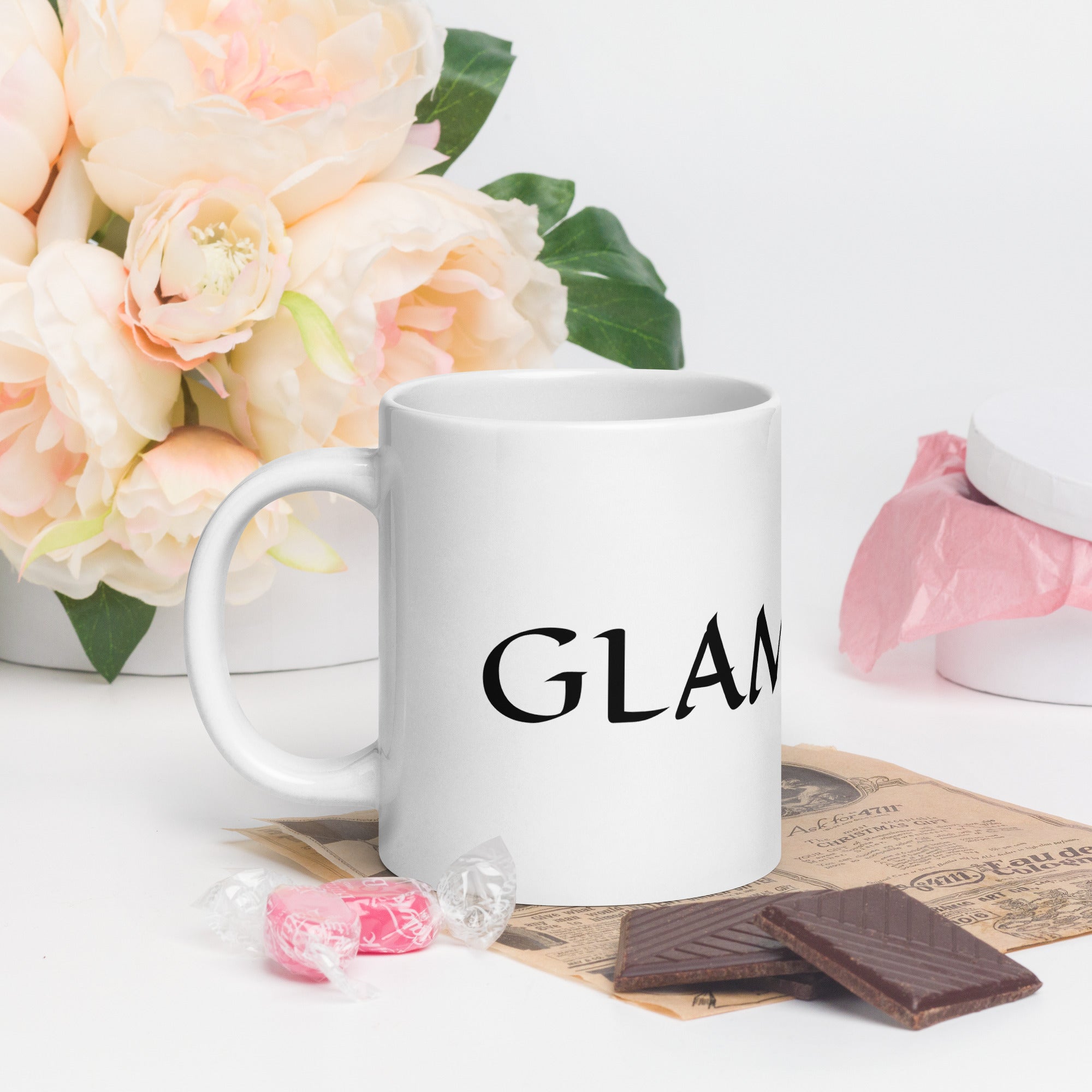 White ceramic glam ma coffee mug with black text surrounded by flowers and chocolates