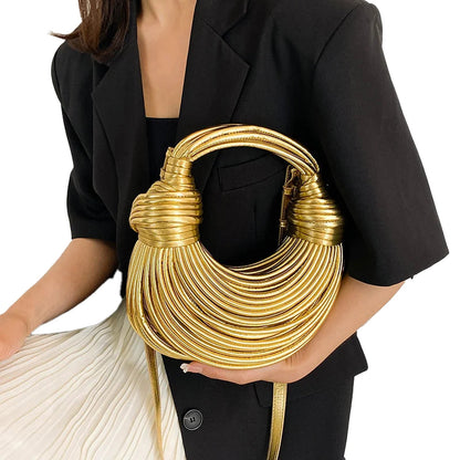 Gold designer handwoven handbag featuring a unique coiled design, held by a model wearing a black blazer
