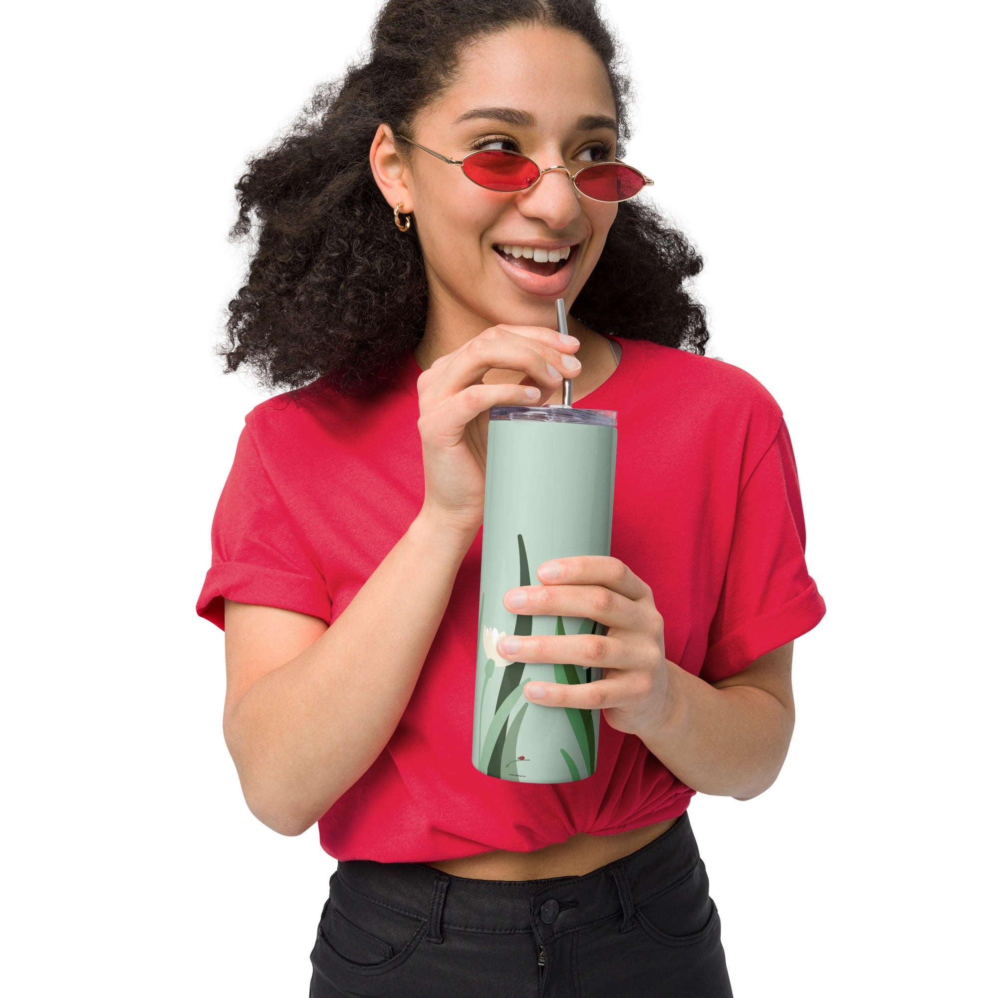 Woman holding green floral stainless steel tumbler with straw and lid while smiling