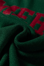 Close-up of a soft green fabric with red lettering of a white MERRY Christmas sweater by LuckeLadybug