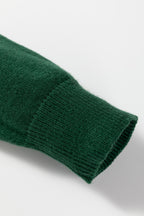 Close-up of a green sweater cuff, showcasing the cozy knit texture of the white MERRY Christmas sweater