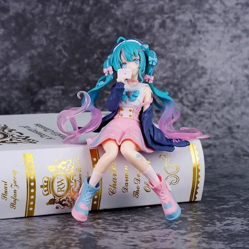 Hatsune and Miku figurine sitting on a book, featuring colorful hair and vibrant outfit details
