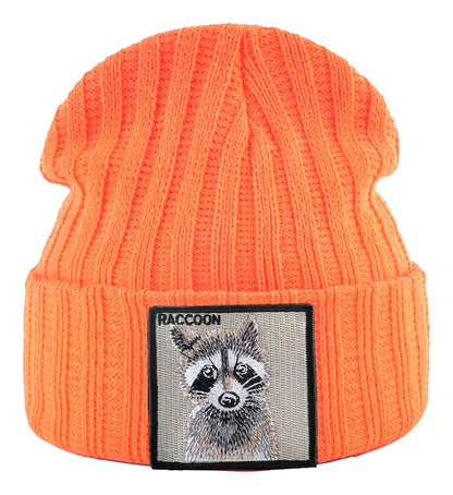 Bright orange knitted beanie hat with patch featuring a raccoon design for a fun outdoor look