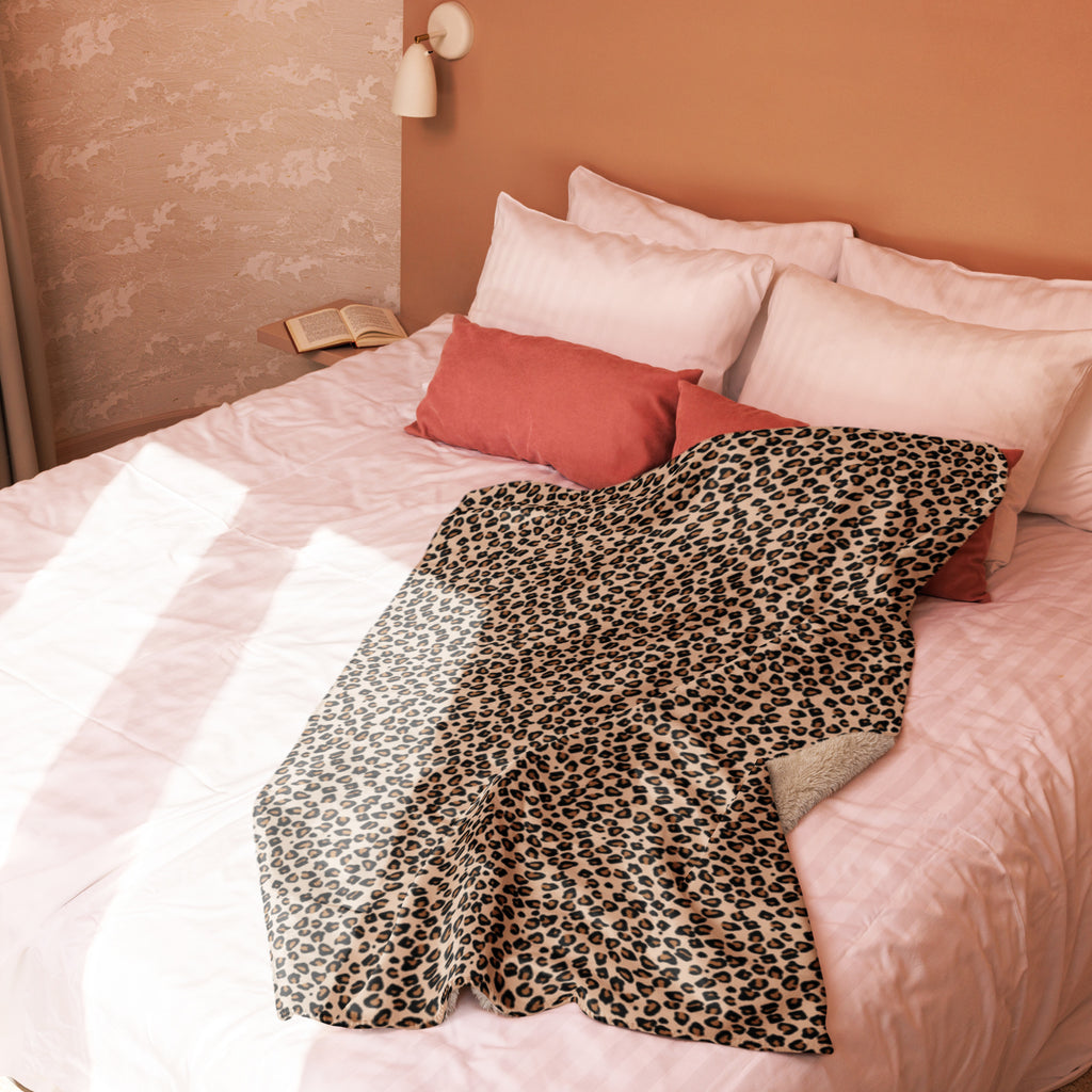 Leopard print sherpa blanket spread on bed with white and pink pillows in cozy bedroom