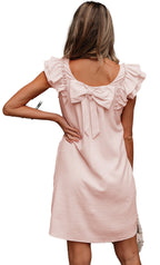Back view of a light pink flutter sleeve mini dress with a bow detail at the neckline