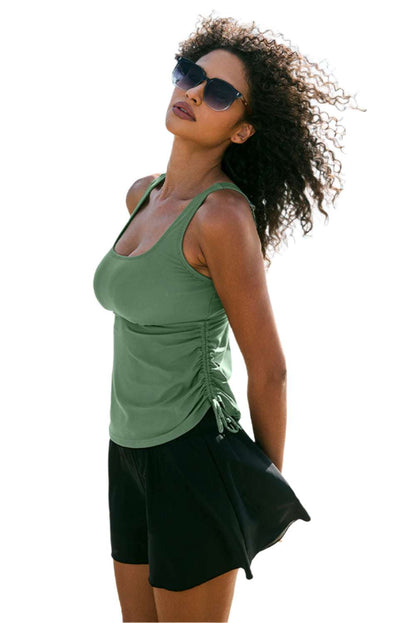 Woman wearing mist green tankini skort set with sunglasses posing outdoors