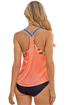 Back view of a woman wearing an orange racerback tankini with striped straps and navy bottoms