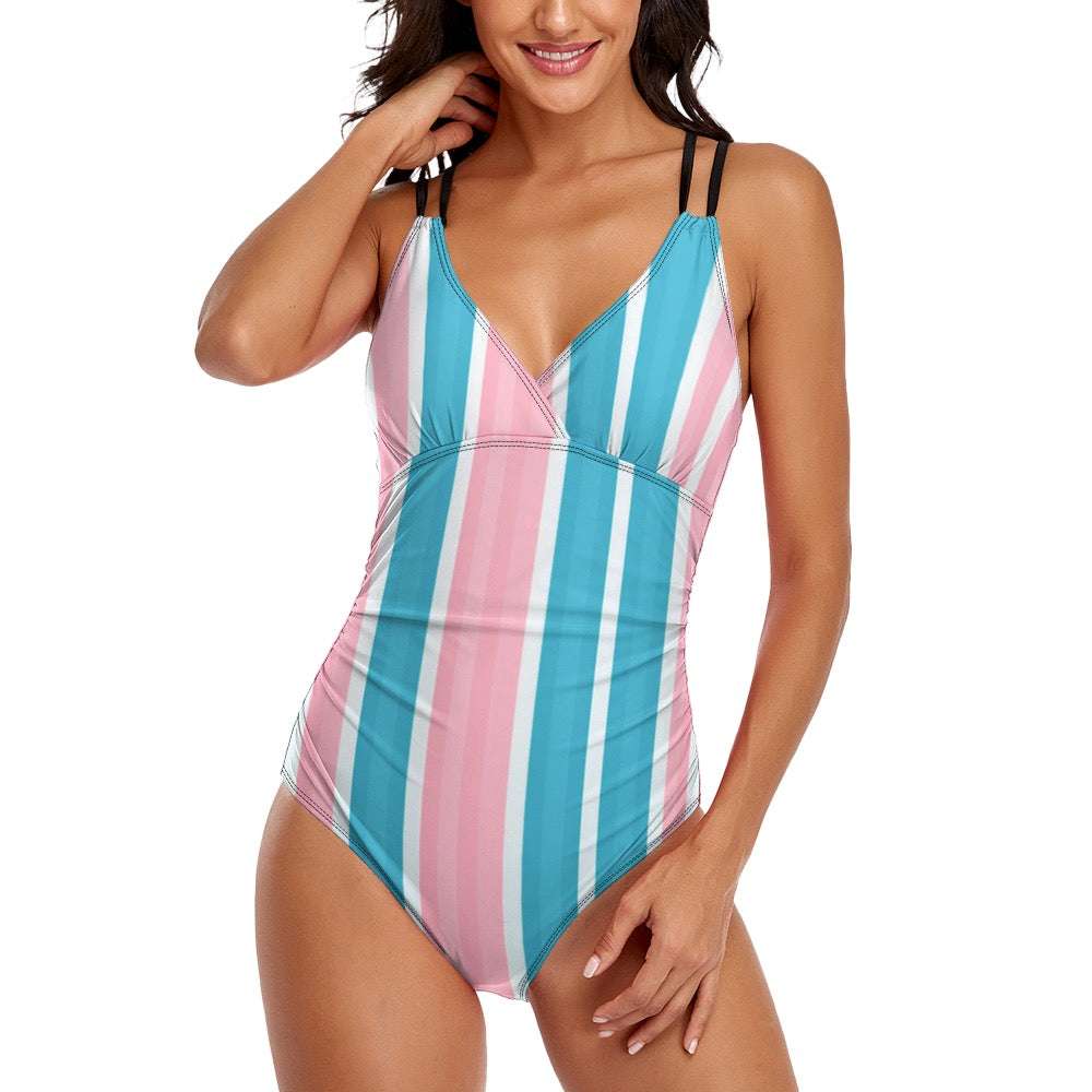 Woman wearing pink striped one piece swimsuit with blue and white vertical stripes and black double shoulder straps