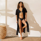 Model wearing a sustainable black string bikini with a black cover-up and sandals