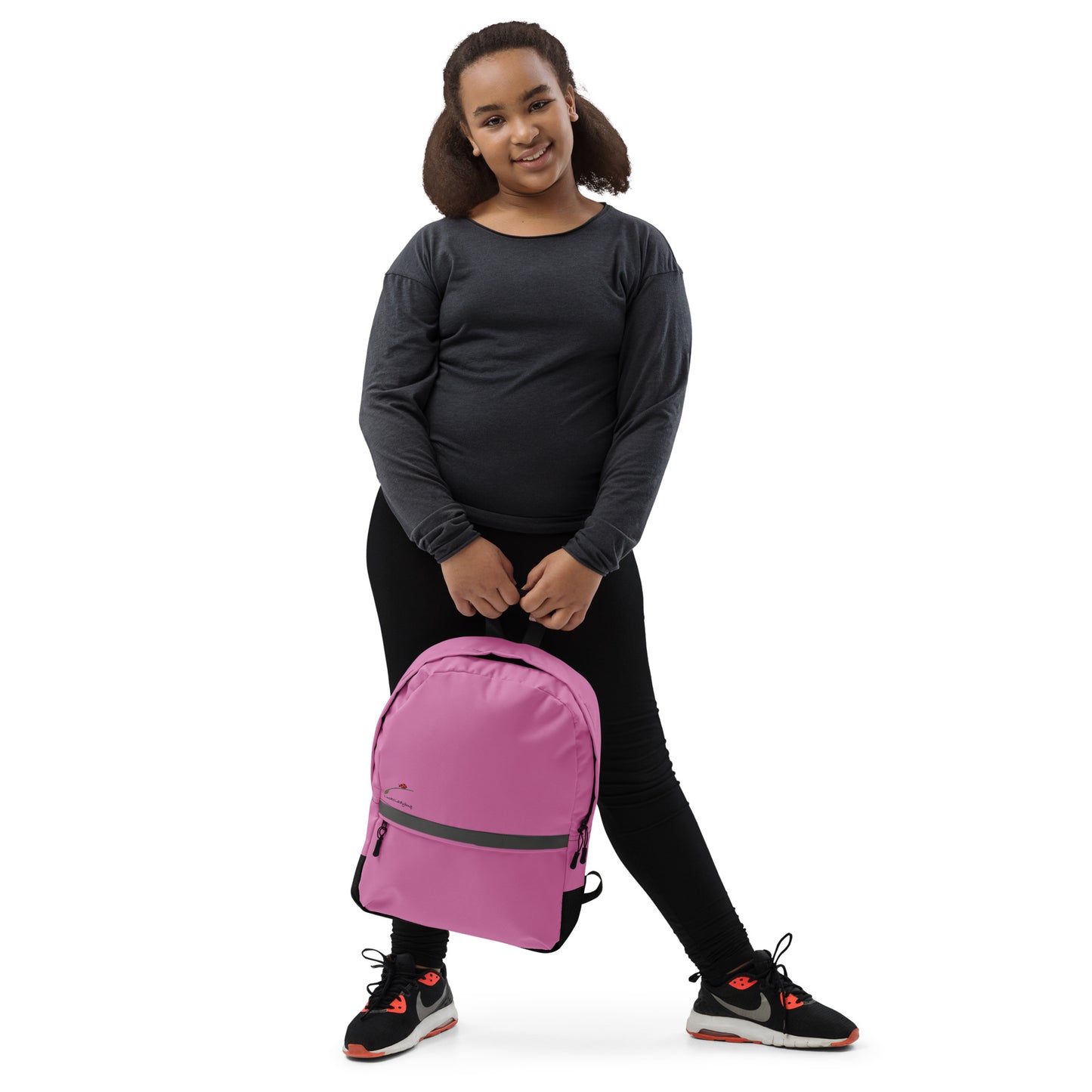 Young girl holding a pink backpack for teens and adults by LuckeLadybug against a white background