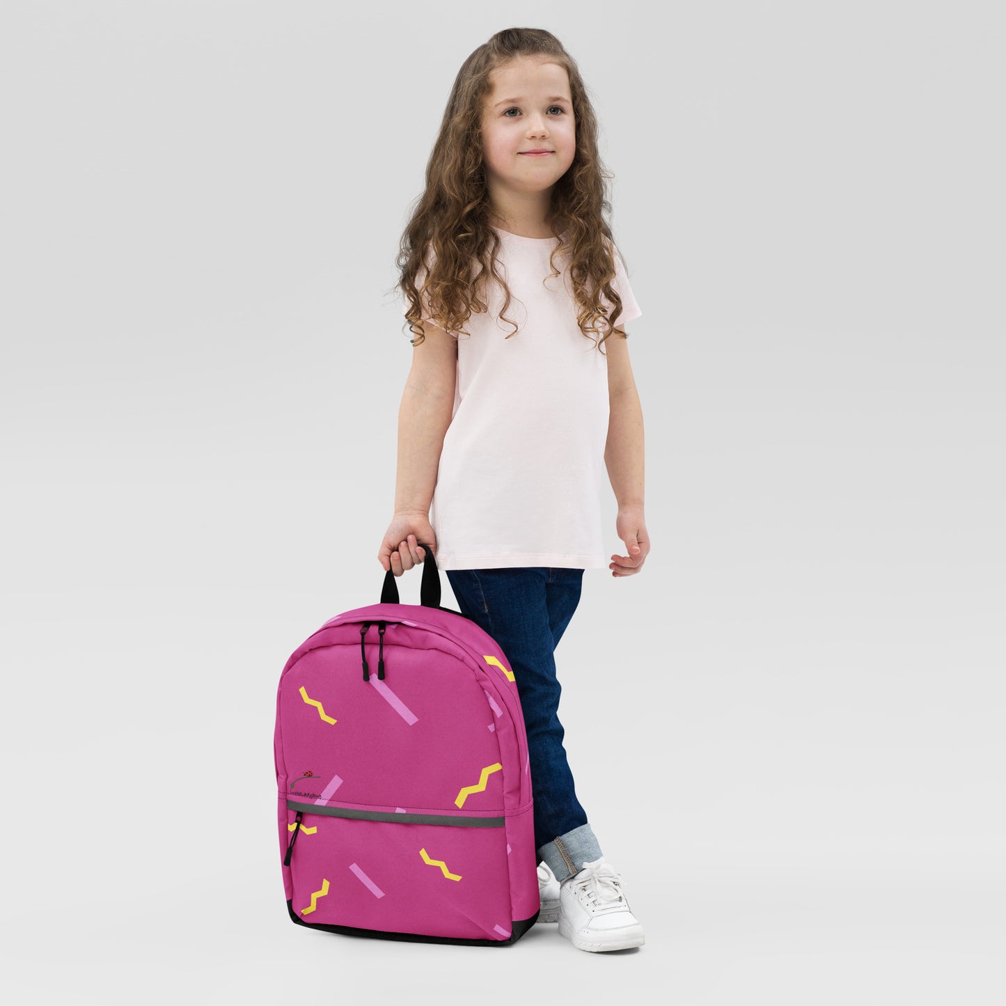 Young girl holding a pink stylish school backpack with yellow and purple abstract patterns