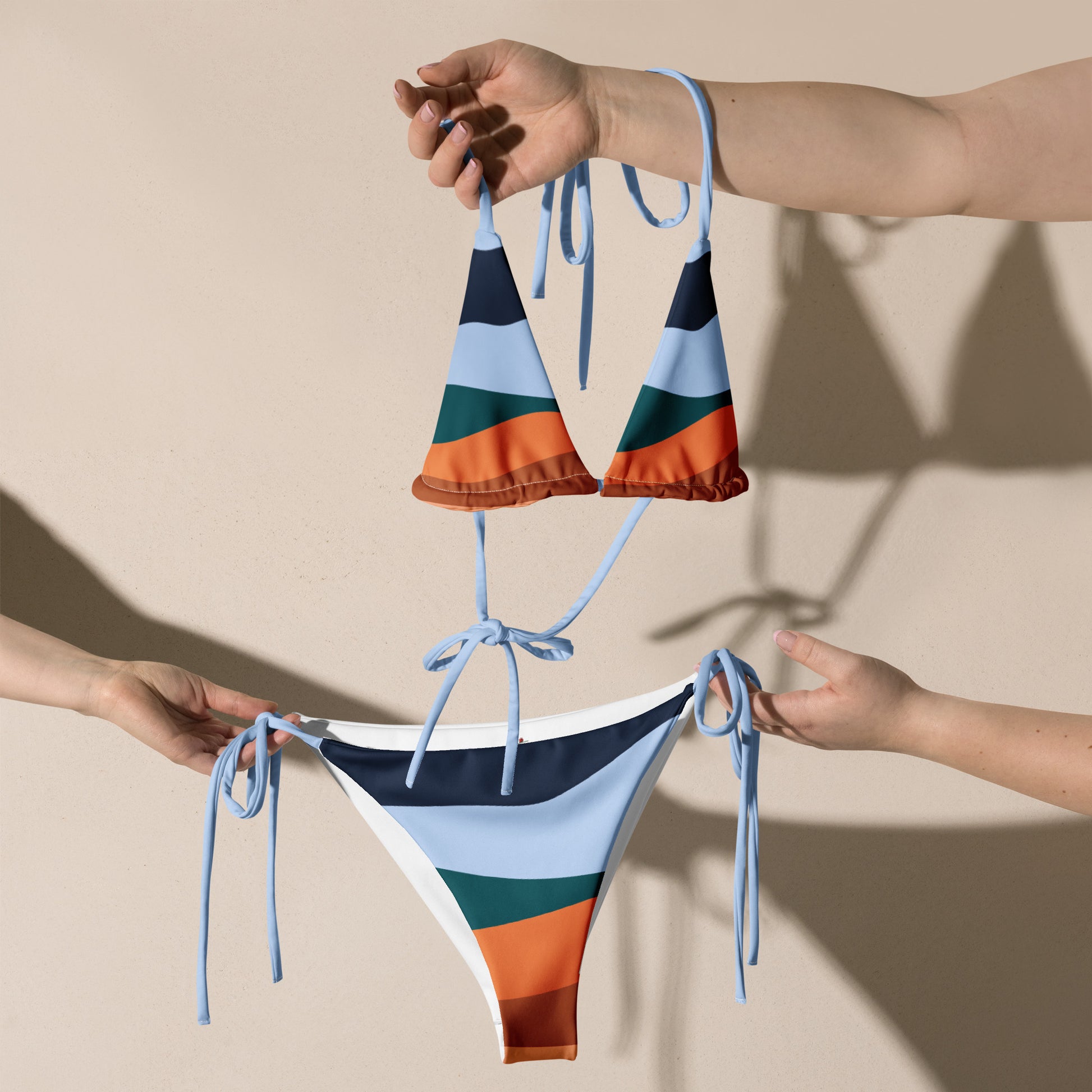 LuckeLadybug multi color bikini for women with blue, orange, green, and black stripes held by two hands