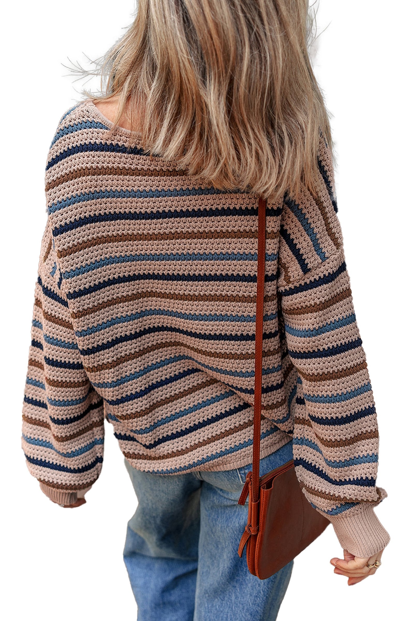 Back view of a multicolor striped knitted sweater with loose fit and wide sleeves, paired with denim jeans