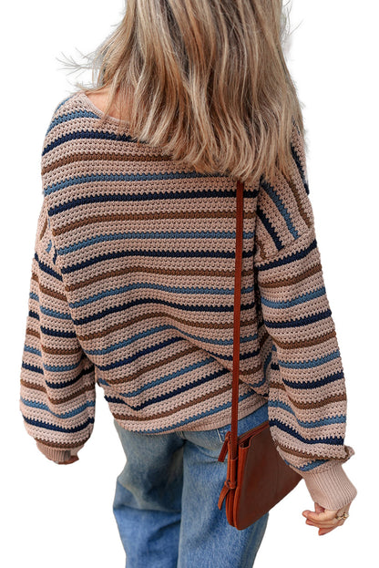 Back view of a multicolor striped knitted sweater with loose fit and wide sleeves, paired with denim jeans