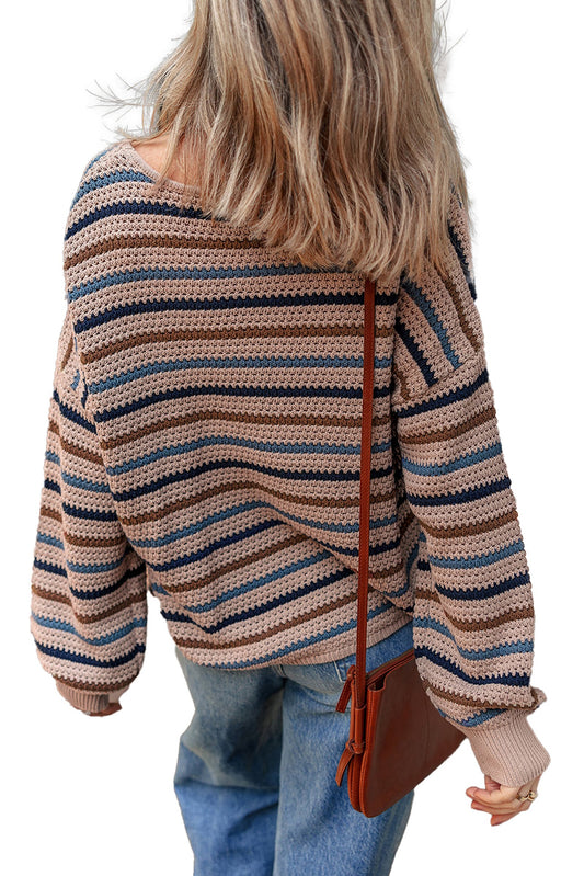 Back view of a multicolor striped knitted sweater with loose fit and wide sleeves, paired with denim jeans