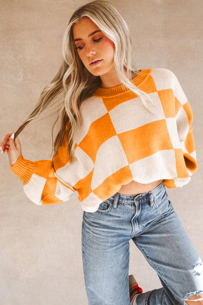 Orange checkered bishop sleeve sweater in a cropped style, paired with high-waisted jeans.