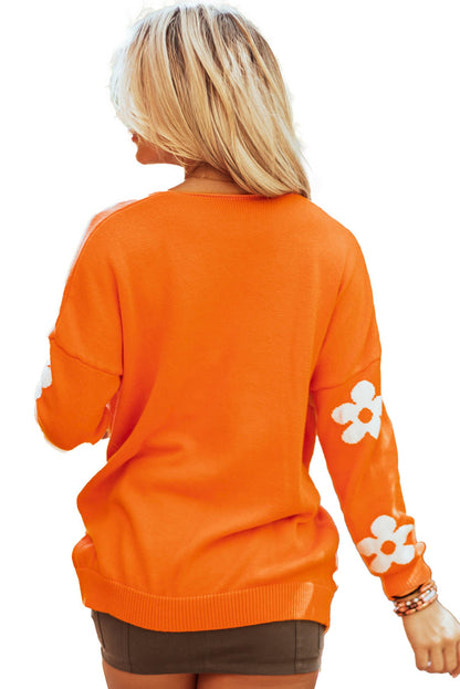 Back view of an orange floral knit cardigan with white flower details on the sleeves