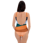 Back view of a woman wearing an orange stripe one-piece swimsuit by LuckeLadybug with multicolor curved stripes