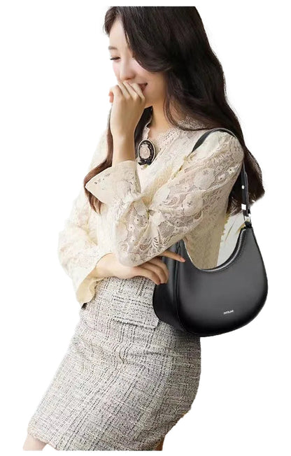 Stylish woman holding a luxury half moon hobo bag, paired with a chic outfit for a modern look