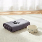 LuckeLadybug LLC absorbent towel in purple with paw print, next to a matching pet food bowl