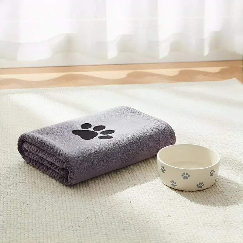 LuckeLadybug LLC absorbent towel in purple with paw print, next to a matching pet food bowl