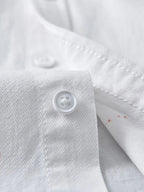 Close-up of white button-up shirt fabric showcasing a button, perfect for plus size clothing for women's fashion.
