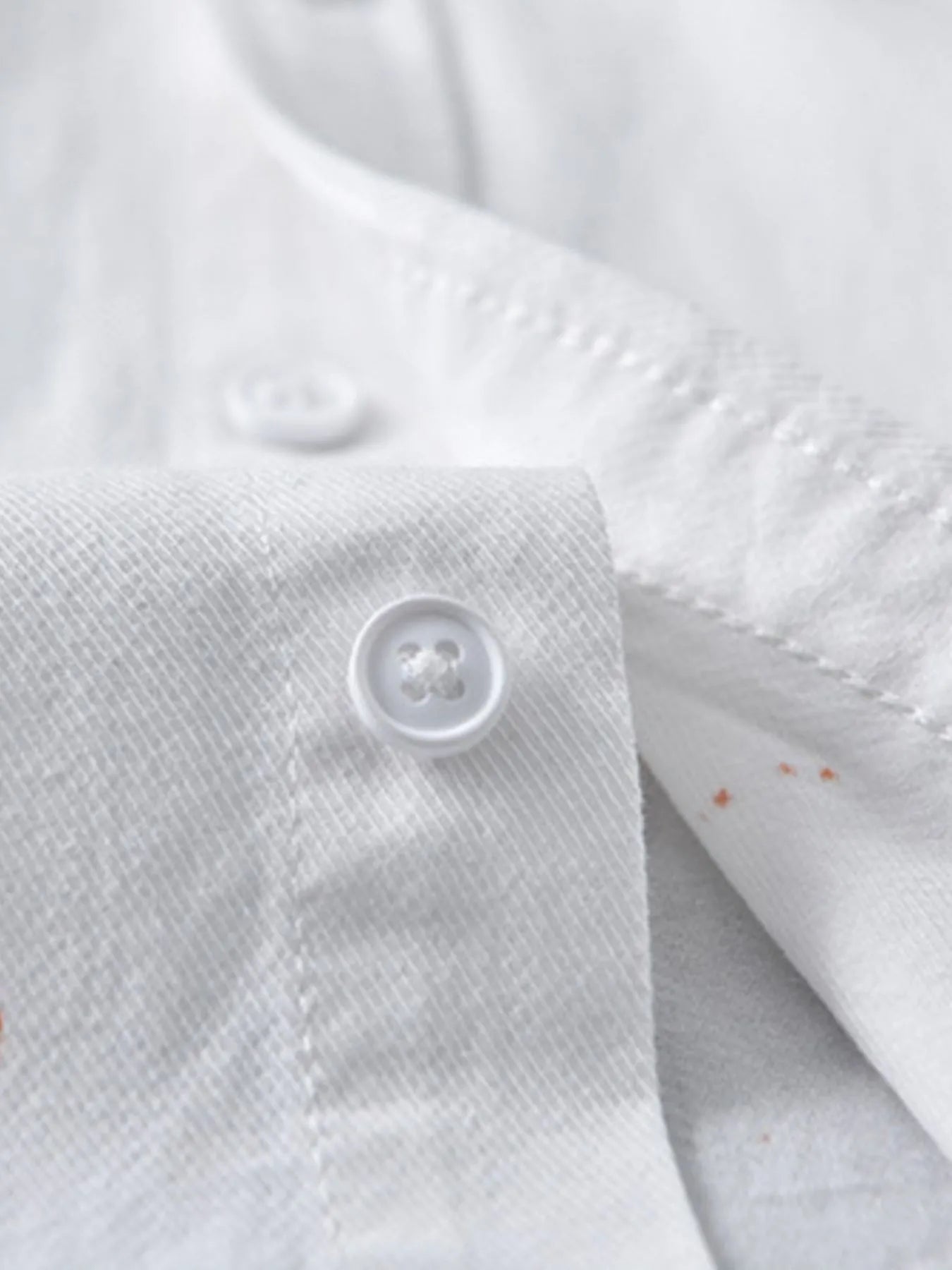 Close-up of white button-up shirt fabric showcasing a button, perfect for plus size clothing for women's fashion.