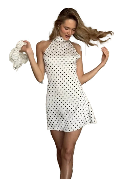 Model wearing a polka dot halter mini dress with playful movement and flowing hair