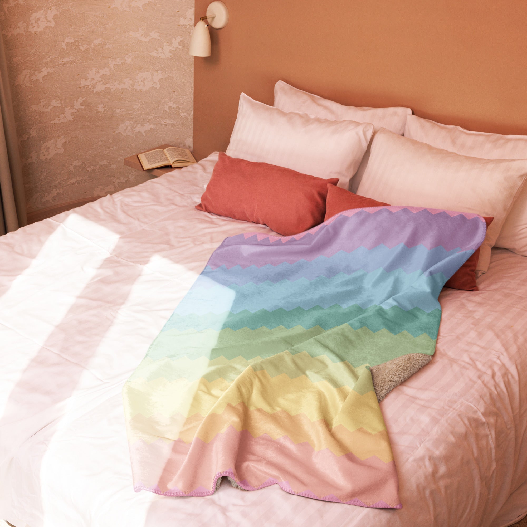 LuckeLadybug rainbow pride sherpa blanket draped over a white bed with pink and red pillows
