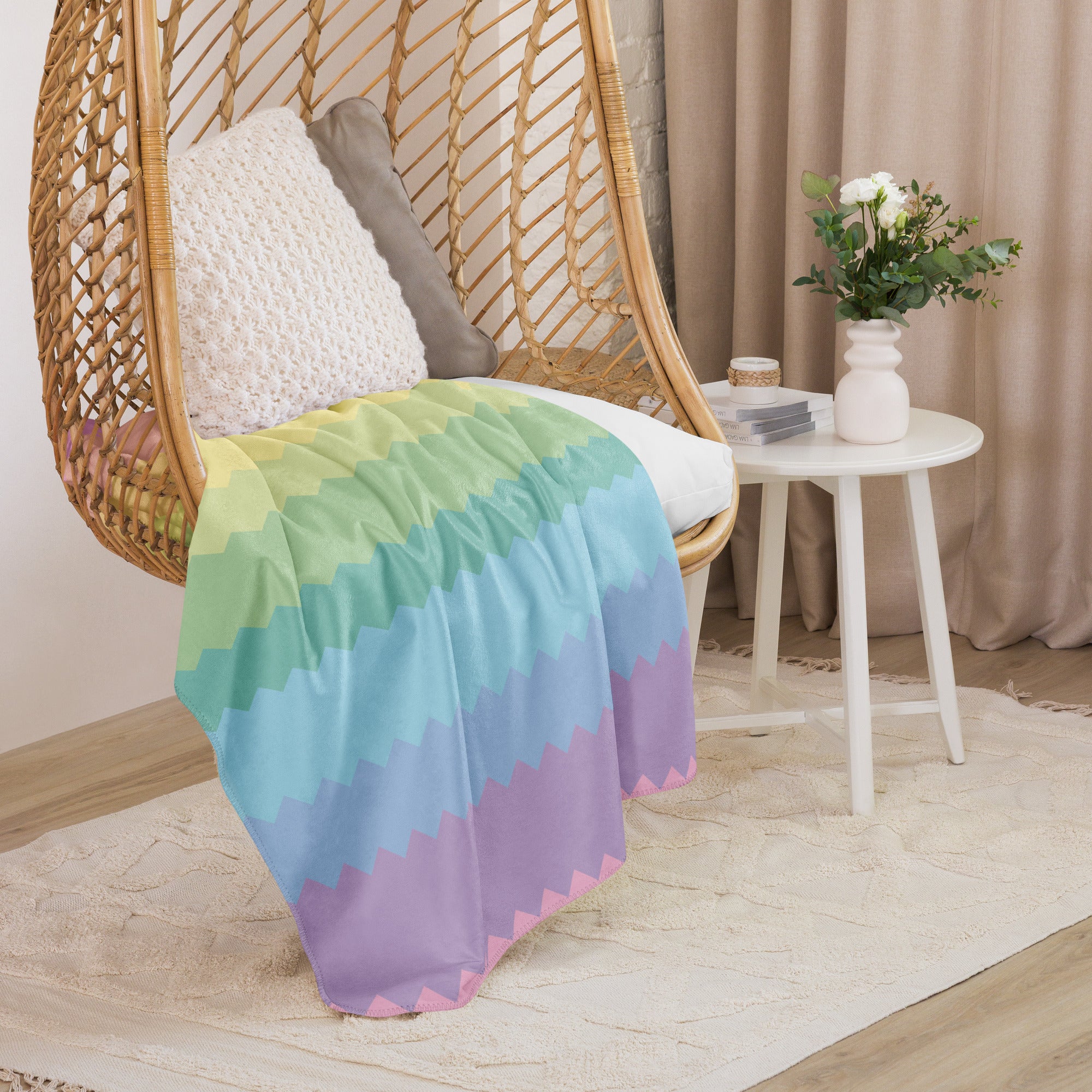 Rainbow pride sherpa blanket draped over wicker hanging chair with cushions in cozy room