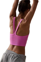 Back view of a woman wearing a pink ribbed cropped cami top with double straps and gray sweatpants