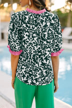 LuckeLadybug LLC ruffled blouse with pink accents against a green backdrop by a pool