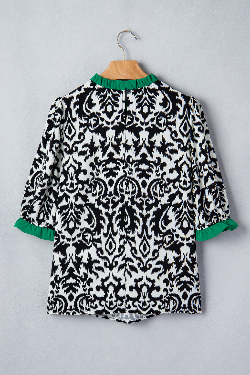 Back view of a black and white patterned ruffled blouse with green accents from LuckeLadybug LLC